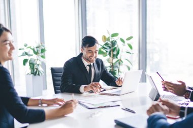Keyifli çalışanlar toplantı masasında oturmuş iş fikirlerini tartışmak ve ilerici proje için başlangıç stratejisi oluşturmak için konferans beyin fırtınası yapıyorlar.