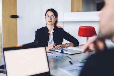Göz koruması için optik gözlüklü kadın girişimci portresi. Erkek meslektaşımla iş birliği yaparken kameraya bakıyor. Finansal web sitesi için kopyalama alanı olan bilgisayar modeli.