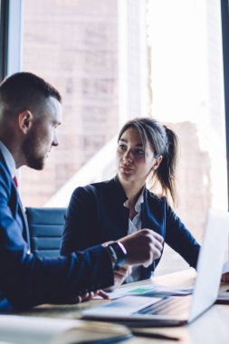 İş kurma projesinin beyin fırtınası sırasında gelir sermayesini tartışan beyaz insanlar, resmi olarak giyinmiş erkek ve bayan meslektaşlar masaüstü bilgisayarlarında dizüstü bilgisayar ve belgelerle işbirliği yapıyorlar.