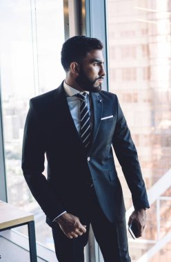 Şirket ofisindeki panoramik pencerenin yanında şık giyinmiş çeşitli meslektaşlar 30 yaşındaki çok ırklı erkek ortaklar üretken işbirliği ve beyin fırtınası brifinglerini tartışıyorlar.