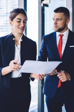 Beyaz erkek ve kadın çalışanlar iş için iş stratejilerini tartışıyor ofis çalışma alanındaki kağıt raporlarını analiz ediyor, resmi olarak giyinmiş meslektaşları mali belgeler hakkında konuşuyor
