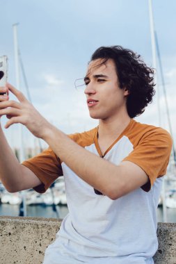 Yaz tatilleri hakkında bilgilendirici video bloğu çeken genç internet etkileyicisi blogcu blog yazarı, internetteki cep telefonu uygulaması üzerinden selfie resimleri yapmak için 4G 'ye bağlanan genç hippi.