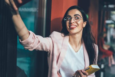 Ders kitabı yazan komik kadın şair molada cep telefonu ön kamerasını kullanarak selfie çekerek fotoğraf çekiyor. Gözlüklü neşeli Gürcü kadın kaldırımda pozitif video çekiyor.