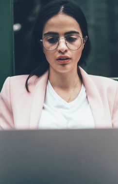 Modern dizüstü bilgisayarda uzak mesafe çalışması yapan yetenekli kadın, klasik gözlüklü bin yıllık kadın çevrimiçi seminer arıyor ya da dijital netbook hakkında bilgi edinmek için özel kıyafet giyiyor.