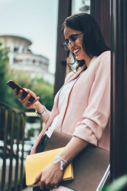 Yeni nesil Z, sosyal ağ kurarken akıllı telefon mesajlarından keyif alıyor. Sayısal cep telefonu aygıtında içerik yayınını paylaşmak için 4G 'yi kullanan gözlüklü samimi bir kadın.