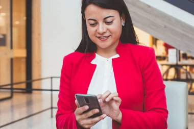 Beyaz bluzlu, parlak ceketli, laptoplu ve cep telefonuyla mesajlaşan genç İspanyol kadın.