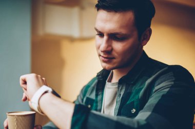 Genç smartwatch dokunmatik ekran arıyorum erkek kahve fincanı, iletişim izlerken görüntü ayarlarını molası için giyilebilir bilgisayar uygulamaları kullanarak hipster adam tutarak yeni ileti hakkında bildirim almak