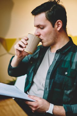 Sınav coworking uzayda içecek zevk için öğrenme analiz bilgisi verilerini tasarımı projenin, düşünceli erkek öğrenci klasörüne okuma sırasında kahve içme zeki hipster adam makaleler