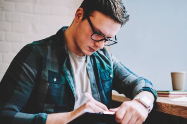 Akıllı erkek serbest yazıda da uzaktan, çalışma yayın önce çalışmak için online ders alan coworking oturan görev yapan zeki hipster adam düzenlemek için Not Defteri'nde konsantre