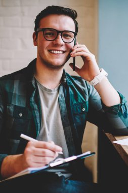 Bilgi eğitim, başarılı hipster adam alan coworking uzak iş üzerinde makale yazma sırasında telefon görüşmesi için dikkat çeken ise telefon danışmanlık ile neşeli adam portresi memnun
