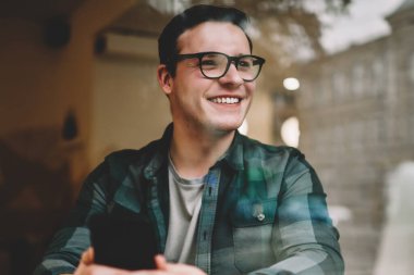 Smartphone için ağ oturma kafe iç ile teknoloji, kahve dükkanı iyi wifi ile uzaktan çalışma müreffeh erkek freelancer memnun kullanarak gözlük mutlu genç adam