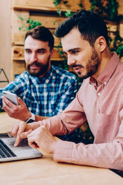 İki erkek meslektaşları üzerinde işbirliği geliştirme projesi uygulaması dizüstü bilgisayar, netbook monitör ofis coworking oturan bilgi hakkında arkadaşıyla danışmanlık işaret hipster adam üzerinde kontrol