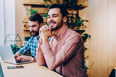 Üniversite kampüsünde başarılı freelancer online başlamak ile arkadaşı ile memnun dizüstü bilgisayarda ödev erkek arkadaşıyla oturan kamera bakarak gülümseyen yakışıklı hipster adam portresi