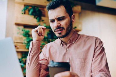 Uzaktan, kızgın genç erkek dizüstü ve üzgün faturaları internet bağlantısı kullanmak için almak posta kontrol çalışma netbook üzerinde dosyaları karşıdan yüklerken hipster adam yazılım hataları ile rahatsız vurguladı