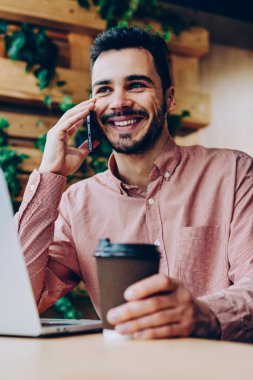 İş yerinde bilgisayarla uzaktan telefon görüşmesi yapan başarılı genç, serbest çalışan yakışıklı, gülümseyen hippi kahve molasında cep telefonu sohbetinden zevk alıyor.