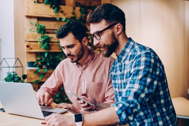 Profesyonel geliştiriciler dizüstü bilgisayarda güncelleme yazılımları birlikte çalışabilirliği kontrol ediyorlar, genç hipster gençler internet sayfasından bilgi okuyor ve internet üzerinden rezervasyon yapıyorlar.