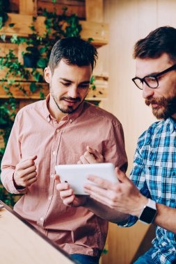 Genç hipster izlemenizi dijital tablet teknolojisiyle, işbirliği ve office coworking konuşurken touchpad hakkında bilgi proje için tarama erkekler birlikte sınavlarına hazırlık eğitimi
