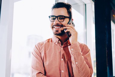 Cep pencere duran, Genç adam tarifeler telefon cep telefonu konuşma bir arkadaşım olması için memnun gülümseyerek telefonu konuşurken rahat kıyafet neşeli hipster adam portresi