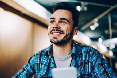 Neşeli yakışıklı adam bakarken hayal tatilini ofis, smartphone ile kahve molası cep telefonu ağ için elinde bir şey hakkında hayal öğrenci gülümseyen genç sohbet ederken