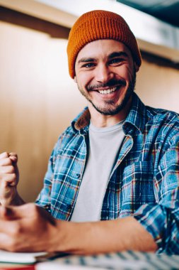 Şapkalı neşeli hippi adamın portresi çevrimiçi yarışmada kazandığı zaferle sevinçten havalara uçuyor telefonu elinde tutarak sınavlardaki başarılarını kutlayan genç adam başarılı bir şekilde mesaj alıyor.