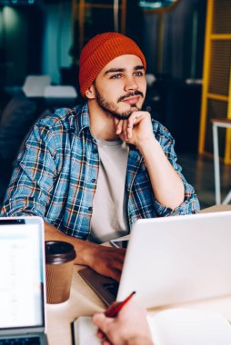 Hayalperest hippi adam çalışma sürecinden uzaklaştırıcı bir şey hayal et. Ofis programcılığında iş arkadaşıyla otururken tatilde olduğunu düşünen düşünceli, olumlu bir adamın görüntüsü.