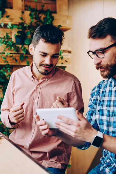 Genç hipster izlemenizi dijital tablet teknolojisiyle, işbirliği ve office coworking konuşurken touchpad hakkında bilgi proje için tarama erkekler birlikte sınavlarına hazırlık eğitimi