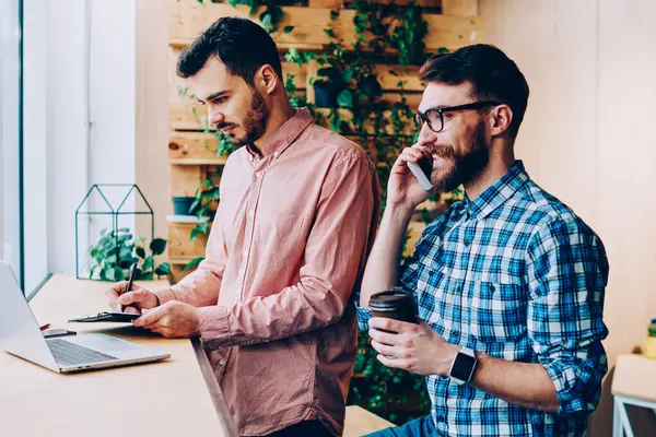 Genç gülümseyen hippi, iş arkadaşı bilgisayar ağlarından bilgi ararken erkek öğrenciler kahve molasında gerçek iletişimi görmezden geliyor.