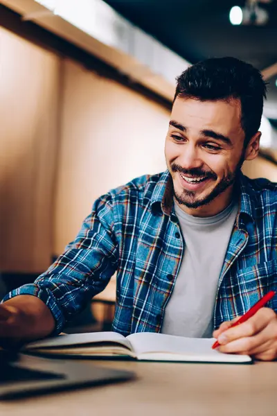 Ödev hazırlama kitaplığı, mutlu erkek öğrenci öğrenme sırasında netbook komik video izleme sırasında dizüstü bilgisayarda sosyal ağlar içeriğine bakın gülüyor neşeli hipster adam göz