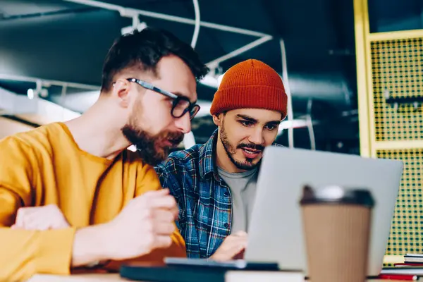 Yetenekli erkek dizüstü bilgisayardaki yazılımı güncellerken programlama üzerine yoğunlaşır. Hippi çocuklar birlikte eğitim web sitesinde webinar izlerler.