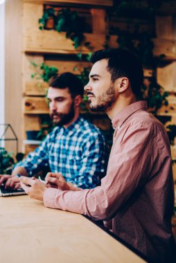 Genç erkek meslektaşları dizüstü bilgisayar, netbook kampüsünde oturan araştırma yapma üniversite proje üzerinde iki hipsters çocuklar takım kullanarak alan coworking içinde serbest uzaktan birlikte çalışma