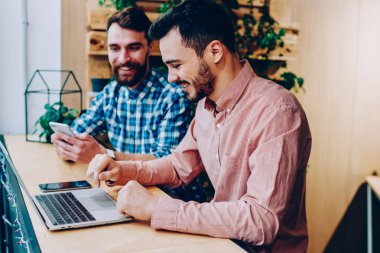 Öğrenme ve ödev college Kampüsü, içinde birlikte müreffeh erkek programları ile araçlar coworking'da oturan iş fikirleri tartışmak için modern dijital cihazlar kullanılarak hipster çocuklar gülümseyen