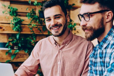 Kamera işbirliği yaparken, birlikte dizüstü bilgisayar kullanan projede çalışan yetenekli erkek programcılar açıklayan bilgi ve fikir onun arkadaşı süre bakarak neşeli yakışıklı adam portresi