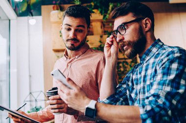 Duygusal hipster adam akıllı telefon bildirim seyir ve şok alış irsaliyesi bill, alma ile genç adam kötü getting haber cep üzerinde hayal kırıklığına duygu onun arkadaşıyla haber okuma vurguladı
