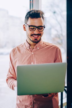 Genç hipster adam gözlük vizyon koruma dizüstü bilgisayar, netbook çalışma için iyi geri bildirimler hakkında mutlu neşeli erkek freelancer Gözat web sayfasında bilgi okumak için memnun