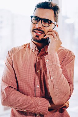 Erkek işadamı cep telefonu operatörüyle konuşurken hoşnutsuz bir yüz ifadesi takınıyor, genç hippi müşteri destek hattını beklemekten rahatsız oluyor, sorunu çözmek için çağrı yapıyor.