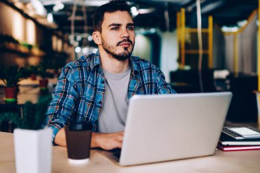 Düşünceli erkek freelancer uzay, netbook ve wifi öğrenme için üniversite kitaplığında kullanarak düşünceli genç öğrenci coworking içinde dizüstü bilgisayar ile oturup çalışma projesi için fikir üzerinde durulması