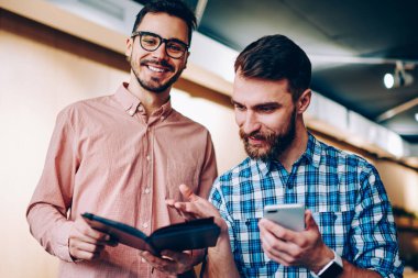 Neşeli yakışıklı erkek iş, ortak proje üzerinde birlikte samimi bir atmosferde işbirliği meslektaşım notlar üzerinde işaret hipster adam için planlama ile not defteri tutan kamera görüntülemenin portre