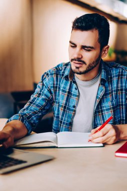 Erkek öğrenci, internetteki internet kursları vasıtasıyla öğrenim görmek için internet üzerinden bilgi topluyor. Sosyal ağlarda yayınlamak için dizüstü bilgisayar yazıları kullanan hippi çocuk.