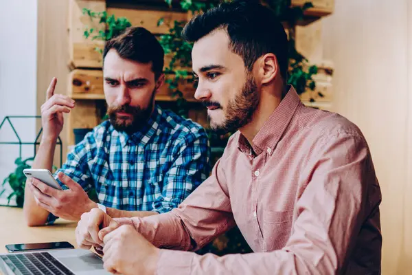 Konsantre erkek birlikte dizüstü üzerinden proje üzerinde işbirliği karar geliştiriciler hesaplamak, ev ödevi görevi kampus içinde netbook üzerinde araştırma yapmak için fikirler tartışırken ciddi hipster çocuklar BT