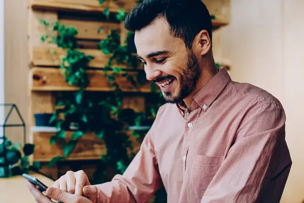 Neşeli hipster adam komik video gülüyor Smartphone'da serbest zaman sırasında genç erkek müreffeh freelancer telefon online kazanç para hareket bildirim almak ile memnun izledim
