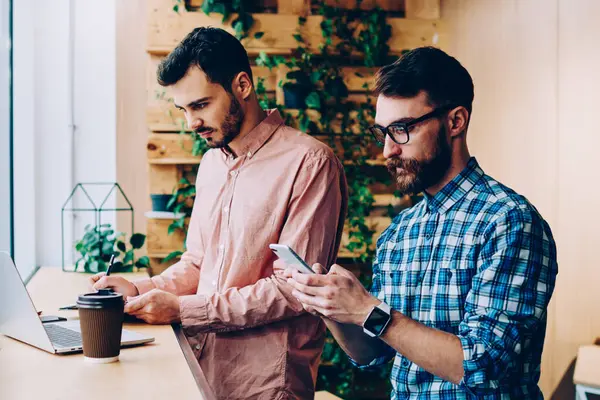 Genç yetenekli erkek bu bilgi için programlama dizüstü bilgisayar ve akıllı telefon üzerinden kontrol üzerinde çalışan geliştiriciler, hipster adam arama numarasına meslektaşı ise cep telefonu üzerinde Web'den Haberler