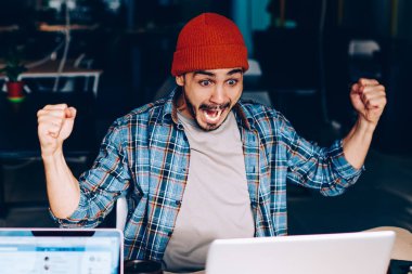 Coşkulu erkek futbol fanatiği takım maçının zaferine hayret ediyor. Çalışma sürecinde çığlık atıyor ve neşeleniyor. Duygusal hipster adam yarışmada kazanmanın harika haberlerini kutluyor.