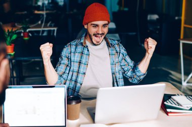 Dizüstü bilgisayarda çalışan erkek çalışanın arka planda ekranı taklit ederken, elleri havada olan duygusal meslektaşı zafer çığlıkları atıyordu. Hipster adam futbol maçı çevirisine hayran kalmıştı.