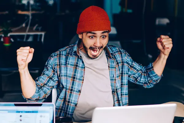 Coşkulu erkek futbol fanatiği takım maçının zaferine hayret ediyor. Çalışma sürecinde çığlık atıyor ve neşeleniyor. Duygusal hipster adam yarışmada kazanmanın harika haberlerini kutluyor.