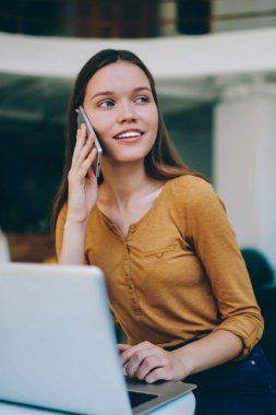 Kafeteryada çalışırken, müşteri hizmetleri ile sohbet için yeni bir akıllı telefon uygulaması aracılığıyla arayan başarılı, tatlı gülüşlü ve başarılı bir kadın yazılım geliştirici.