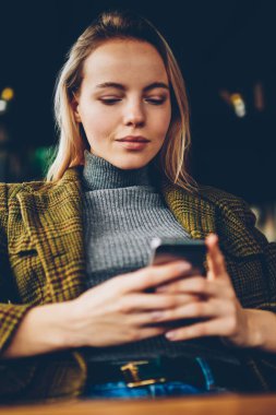 Modern smartphone kafede dinlenme ücretsiz Wi-Fi bağlı haberleri okumak için şık giyimli genç işkadını sosyal ağlarda profil güncelleştirme sarı saçlı. Kadın blogger cep üzerinde sohbet