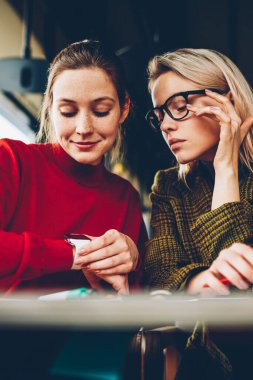 Eğitim zaman alan coworking içinde düzenlemek için düşünceli öğrenciler modern smartwatch göstermek vasıl arıyorum. Hippi kız kafe iç dostu toplantı sırasında kol saati kontrol