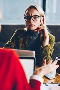 Kadın girişimci dikkatle iş toplantı ve modern dizüstü bilgisayarlar mesafe iş sırasında meslektaşım dinleme konsantre. Üretken strateji tartışmaya Eyewear dalgın genç kadın