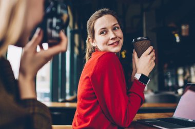 Lezzetli kafein içecek poz ve odaklanan ve coworking boş zamanlarında vintage kamerada fotoğraf yapma yetenekli kadın Amatör süre gülümseyerek elinde olan neşeli kadın üzerinde seçici odak