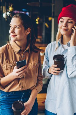 Smartphone üzerinde arama ve düşünme ve coworking zamanında rekreasyon zevk pencereden dışarı bakarak elinde gitmek için en iyi rüya gibi arkadaşıyla kahve iken işleç ile konuşurken şık hippi kız